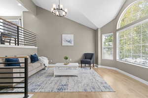 Living area featuring vaulted ceiling, wood finished floors, and a chandelier