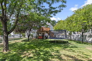 Fenced backyard with a trampoline and a wooden deck