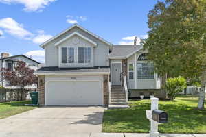 Tri-level home featuring brick siding, a garage, driveway, and a shingled roof