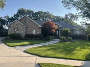 French country inspired facade with a front lawn, brick siding, and stone siding