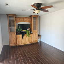 Unfurnished living room with a ceiling fan and dark wood finished floors