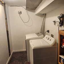 Laundry area featuring a textured wall and washing machine and dryer