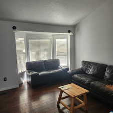 Living area with a textured ceiling and wood-type flooring