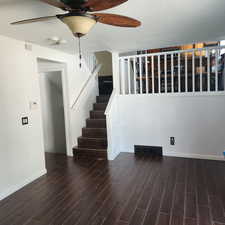 Unfurnished living room featuring ceiling fan, stairs, and wood finish floors