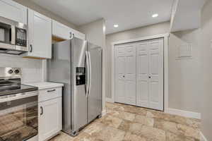 Kitchen featuring appliances with stainless steel finishes, white cabinets, backsplash, light countertops, and recessed lighting