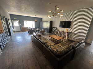 Living area with a textured ceiling, a chandelier, and wood finished floors