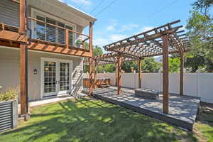 Fenced backyard featuring a pergola, a hot tub, a deck, and french doors