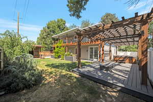 Fenced backyard featuring a hot tub, a pergola, and a deck