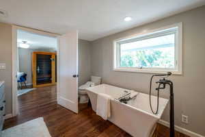 Full bathroom featuring wood finished floors, a soaking tub, and vanity