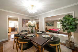 Dining space featuring wood finished floors, billiards, a chandelier, and ornamental molding