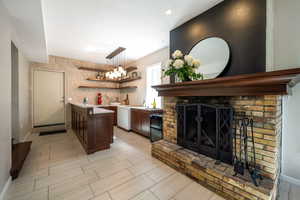 Kitchen featuring light countertops, open shelves, a brick fireplace, wood tiled floors, and a peninsula