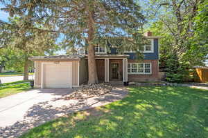 View of front of property featuring a garage, brick siding, driveway, board and batten siding, and a chimney