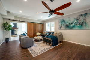 Living area with crown molding, a barn door, recessed lighting, a ceiling fan, and wood finished floors