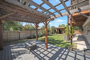 Wooden deck with a pergola, a fenced backyard, and an outdoor structure