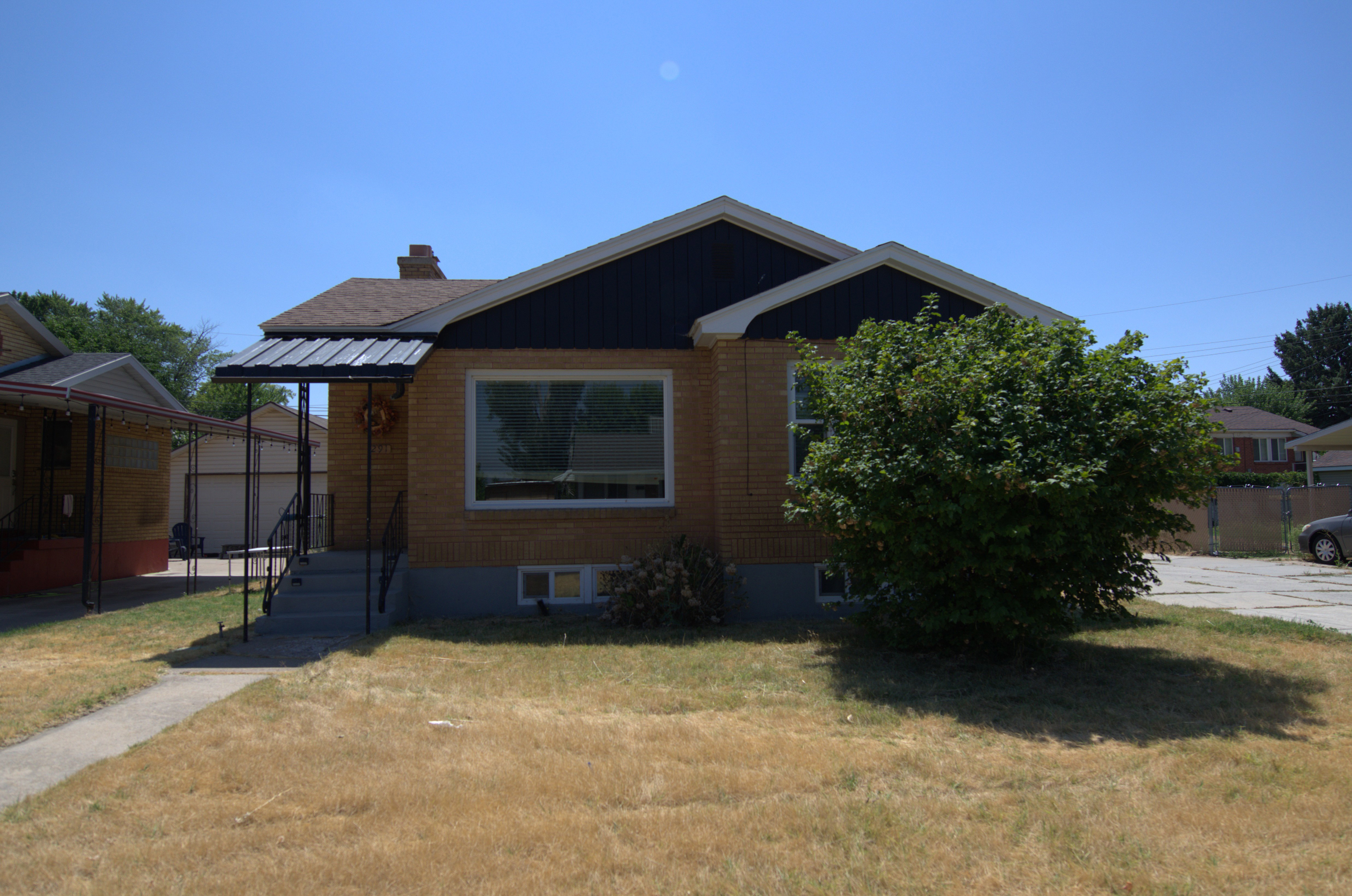 Bungalow-style home with a chimney, brick siding, and a front yard