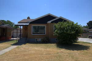 Bungalow-style home with a chimney, brick siding, and a front yard