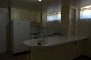 Kitchen with white appliances, plenty of natural light, a peninsula, and white cabinetry
