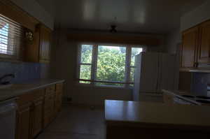 Kitchen featuring decorative backsplash, white appliances, light countertops, and extractor fan