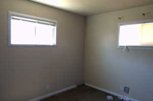 Spare room featuring dark carpet and baseboards