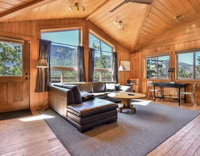 Living room with hardwood / wood-style floors, wooden ceiling, wood walls, vaulted ceiling, and rail lighting