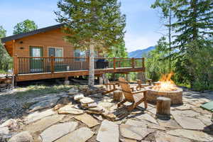View of patio featuring an outdoor fire pit and a deck with mountain view