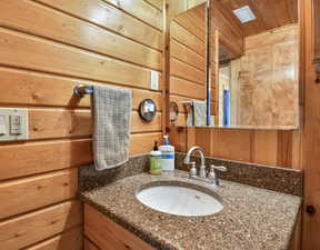 Bathroom featuring wood walls, vanity, and wood ceiling