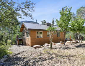 View of property exterior with a metal roof, a chimney, a deck, and stairway