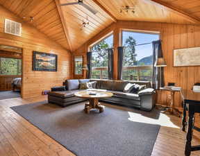 Living room with hardwood / wood-style floors, lofted ceiling, wooden walls, wooden ceiling, and a mountain view