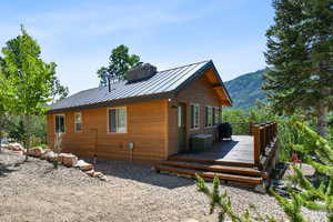 View of property exterior with a wooden deck, a metal roof, and a chimney
