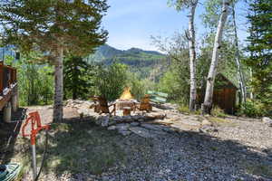 View of yard with a view of trees, a fire pit, and a mountain view