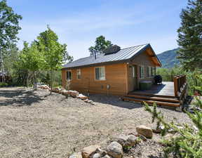 Rear view of property featuring a wooden deck, a metal roof, a chimney, and a standing seam roof