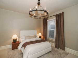Carpeted bedroom featuring baseboards and a chandelier