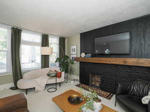 Carpeted living room with baseboards and a fireplace with flush hearth