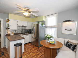 Kitchen featuring dark countertops, stainless steel fridge with ice dispenser, backsplash, dark wood-style flooring, and a textured ceiling