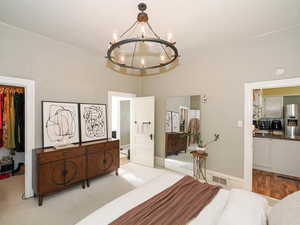 Bedroom with a spacious closet, stainless steel fridge, and a chandelier