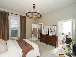 Bedroom with light carpet, multiple windows, a spacious closet, and a chandelier
