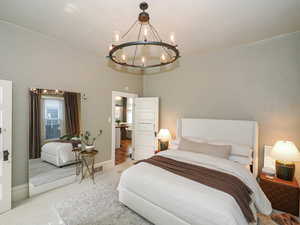 Carpeted bedroom featuring a chandelier and baseboards