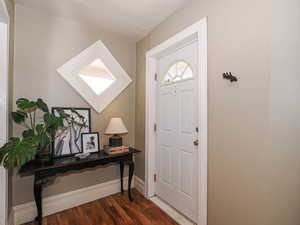 Foyer with dark wood-type flooring and baseboards