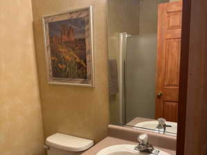 Bathroom featuring a textured wall, vanity, and a shower