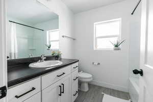 Bathroom featuring wood finished floors, vanity, and shower / bath combo