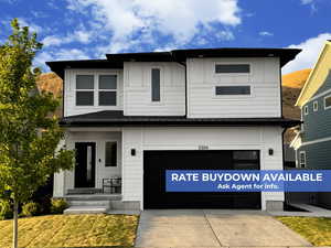 View of front of house with an attached garage, concrete driveway, and covered porch
