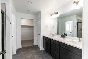 Primary bathroom featuring double vanity, a spacious closet, and a upgraded shower.