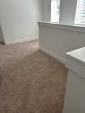 Spare room featuring light colored carpet and baseboards