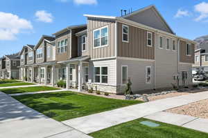 Modern home with a residential view, board and batten siding, stone siding, and a front yard