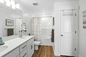 Full bath featuring wood finished floors, double vanity, and shower / bathtub combination with curtain
