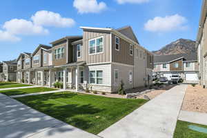 View of front facade with a residential view, board and batten siding, stone siding, and a front lawn