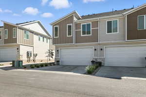 View of front of house featuring stone siding, board and batten siding, concrete driveway, and an attached garage