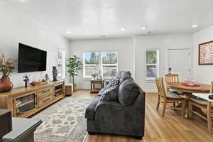 Living area featuring light wood finished floors, a textured ceiling, and recessed lighting