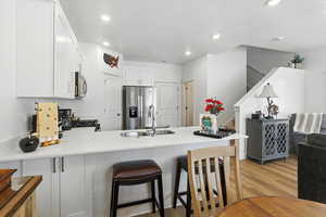 Kitchen with a peninsula, light wood-style floors, appliances with stainless steel finishes, white cabinetry, and a textured ceiling