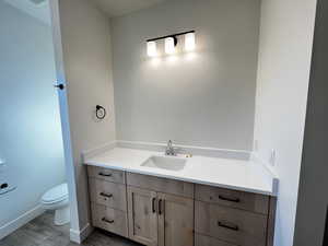 Half bath with vanity and dark wood-type flooring